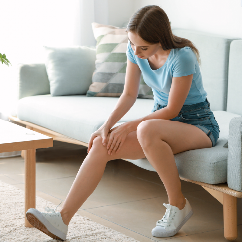 mulher sentada em sofá com a mão no joelho direito