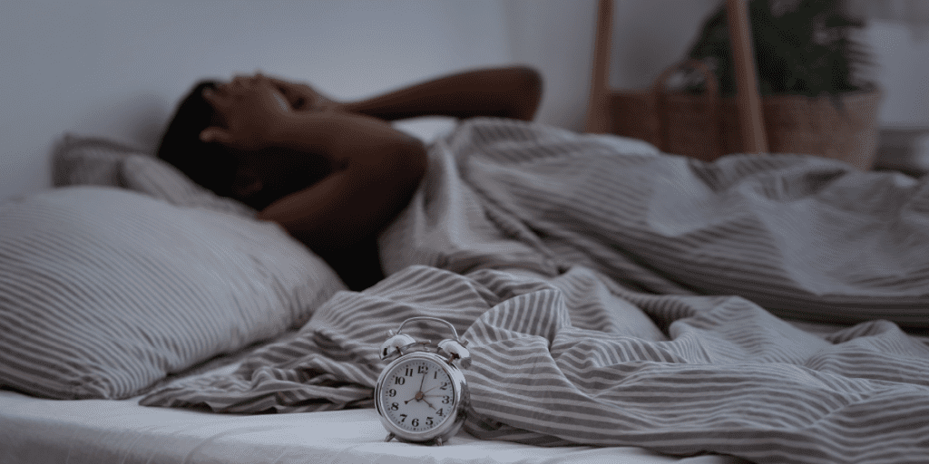 mulher deitada na cama com insonia, dificuldade para dormir